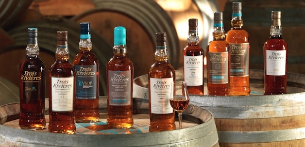 This is a photo of nine bottles of Trois Rivières rum on wooden casks.